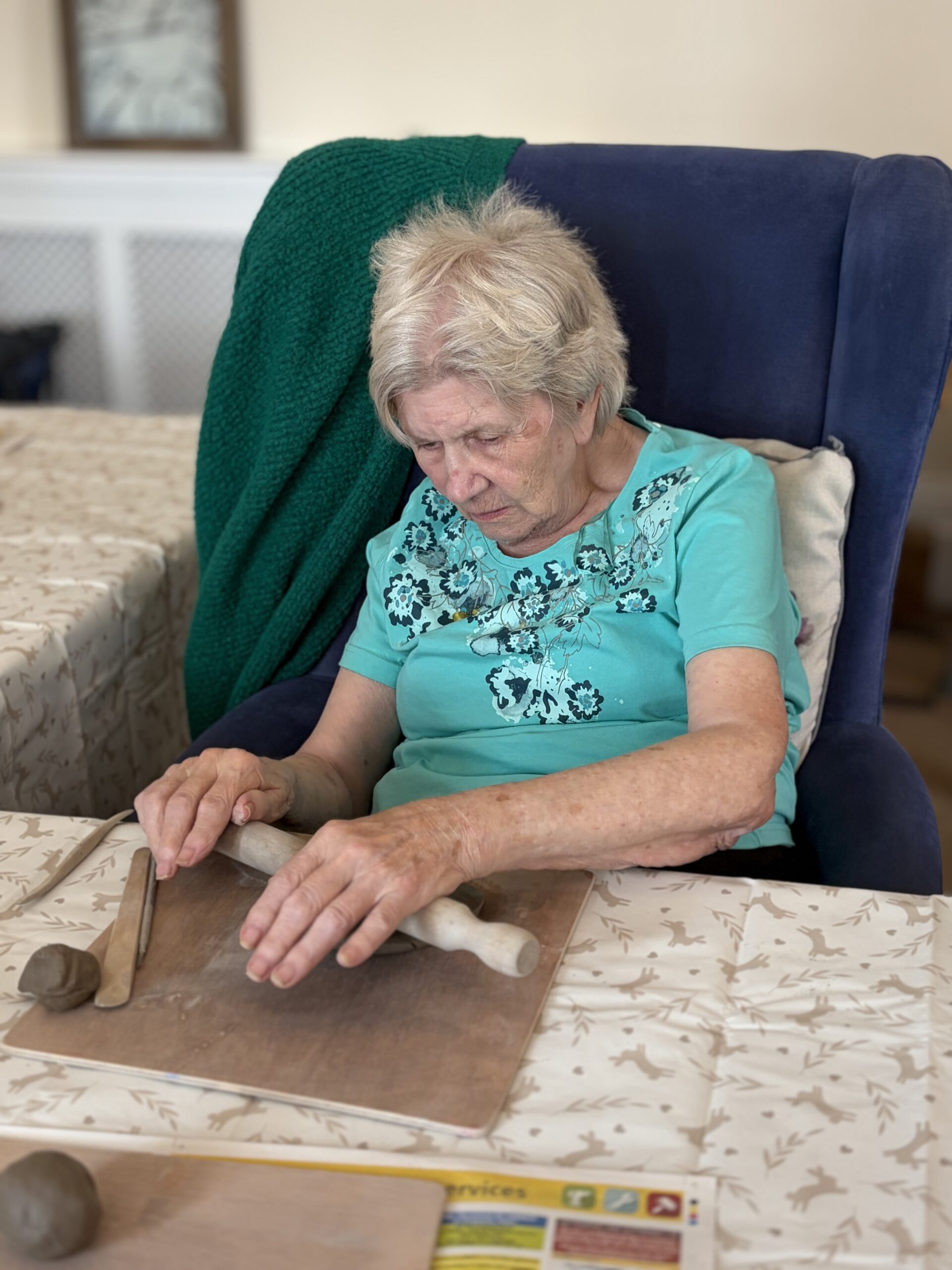 Female resident rolling a piece of clay with a rolling pin