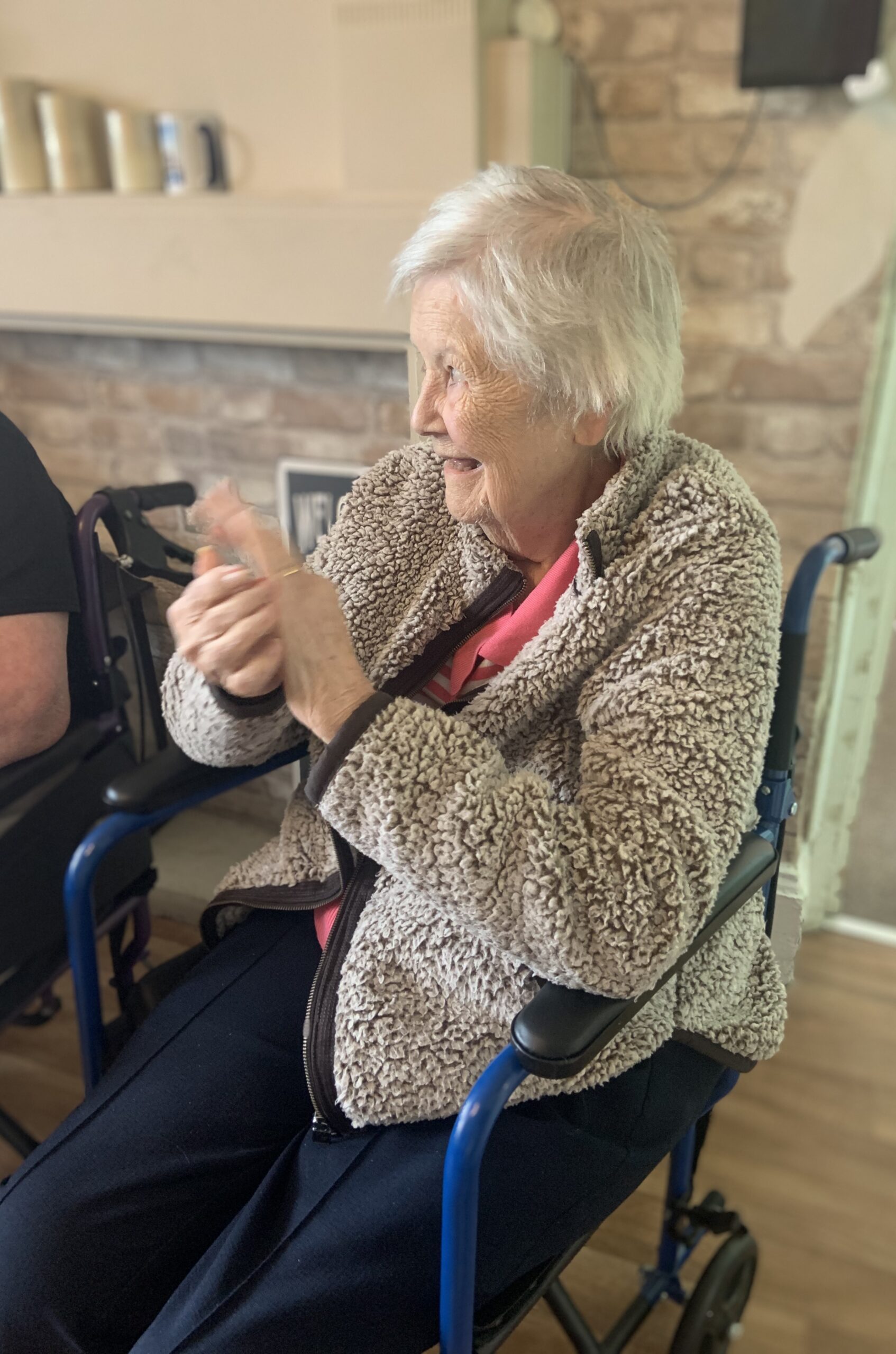 Female resident seated clapping along to the music and smiling