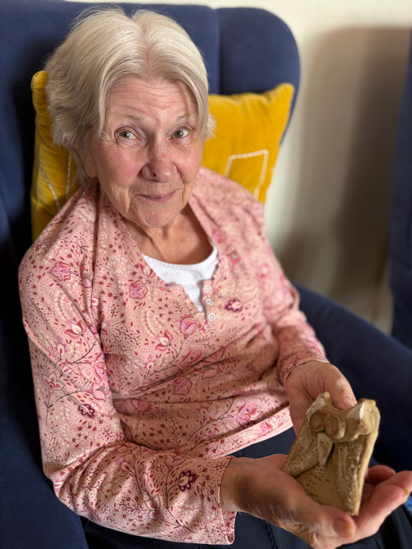 Female resident smiling, holding her pottery owl