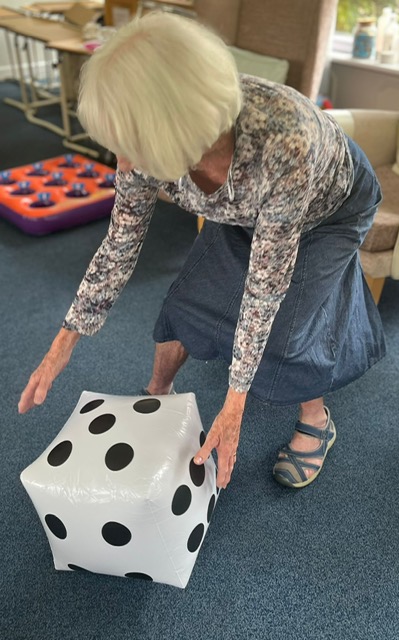 Jean rolling a large blow-up dice along the floor