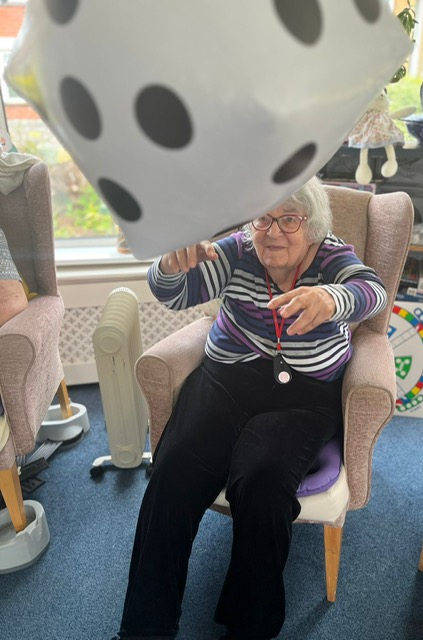 Maggie seated throwing a large blow-up dice in the air