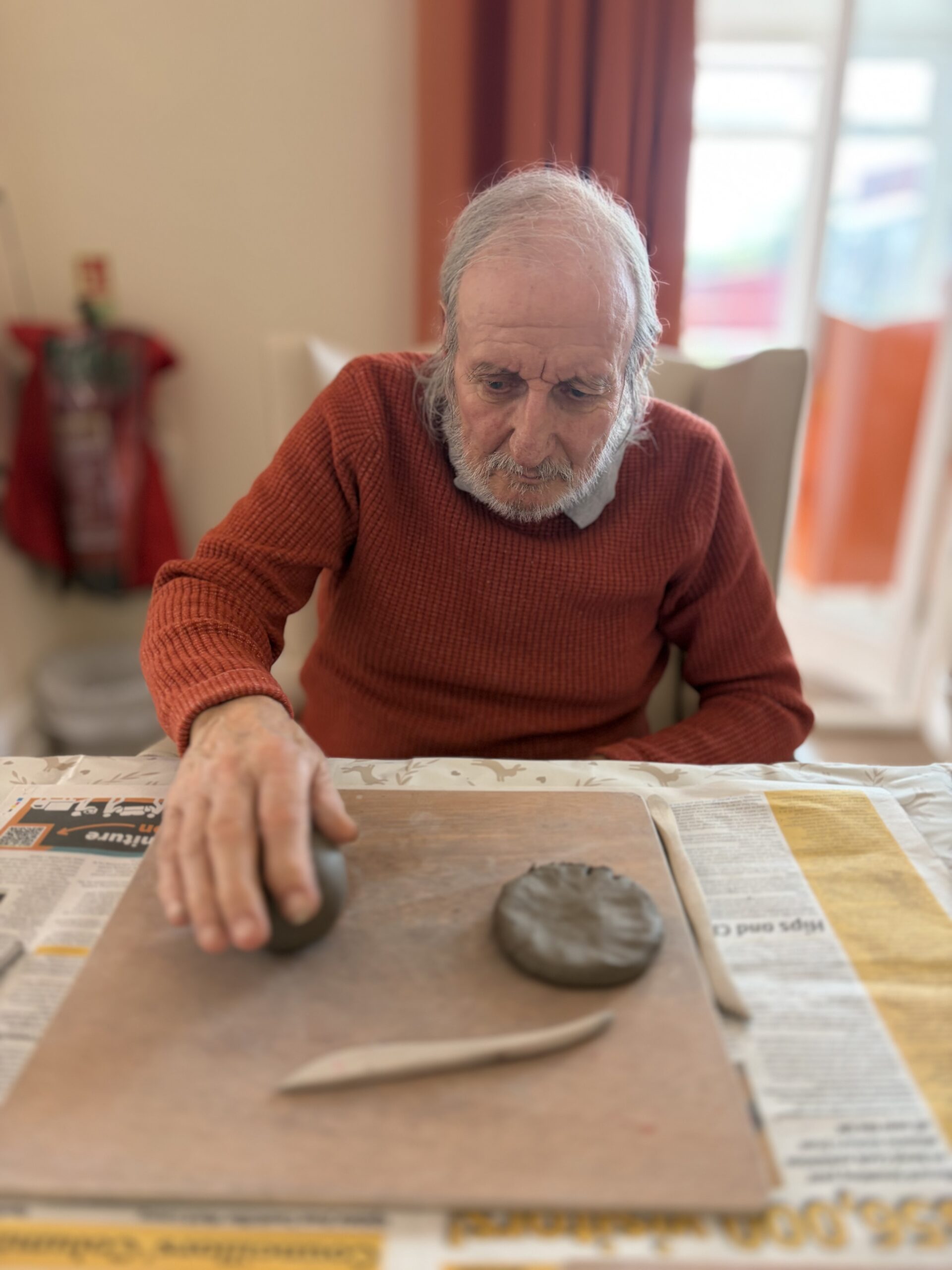 Male resident flattening a piece of clay with his hand