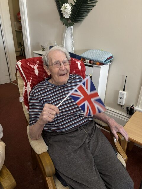 Male resident listening to Zara waving his flag smiling