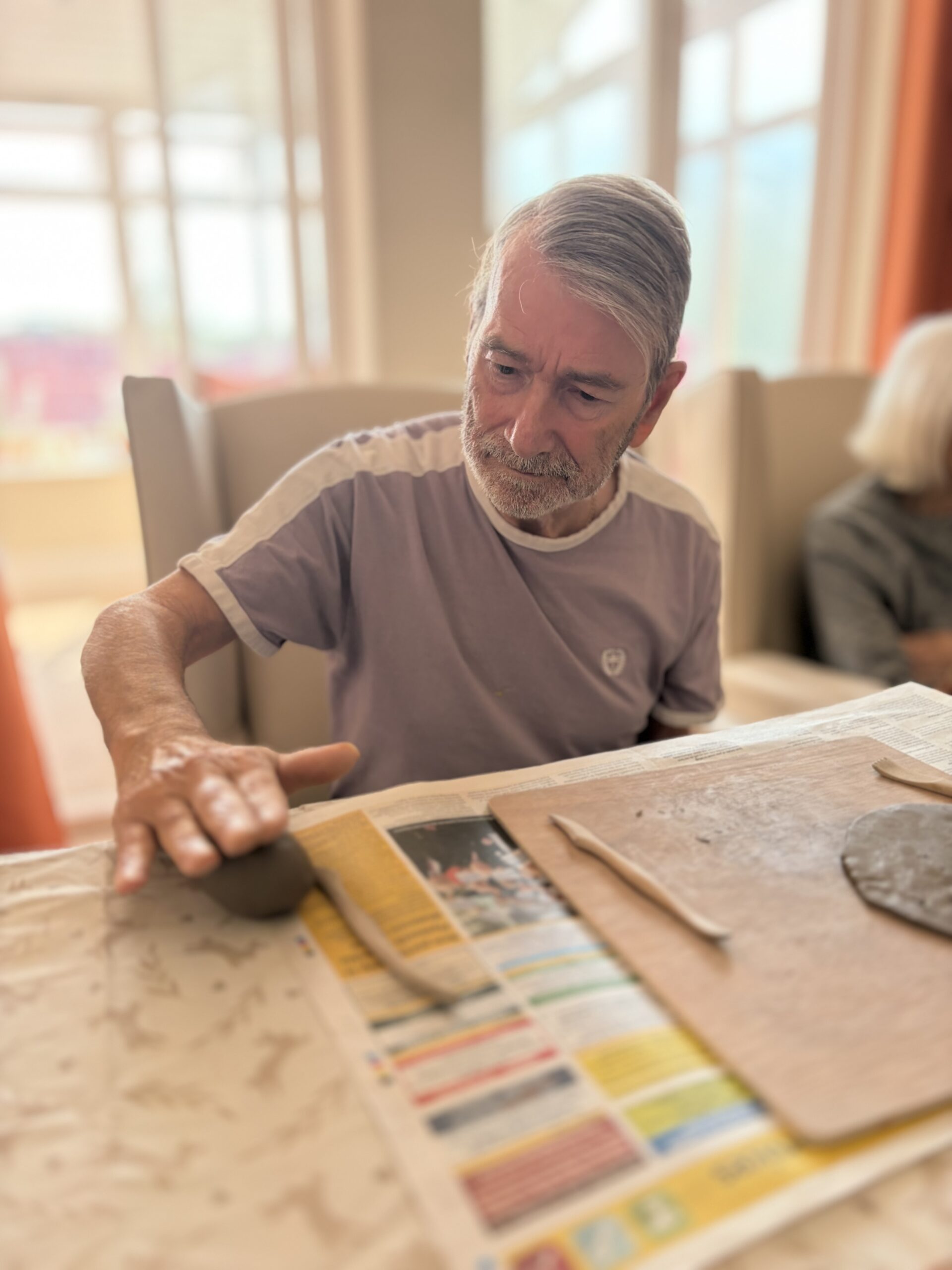 Male resident rolling a piece of clay with the palm of his hand