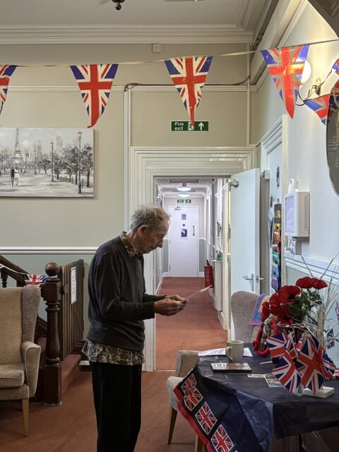 Male resident standing at a table of WW2 memorabilia reading an info sheet