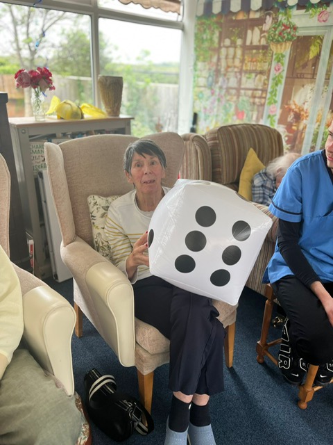 Violet seated holding a large blow-up dice