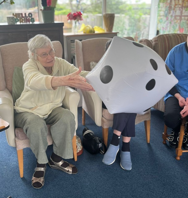 Wendy seated throwing a large blow-up dice